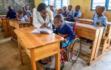 Imagen de menores en un aula en la que se ve a Abraham con la maestra 