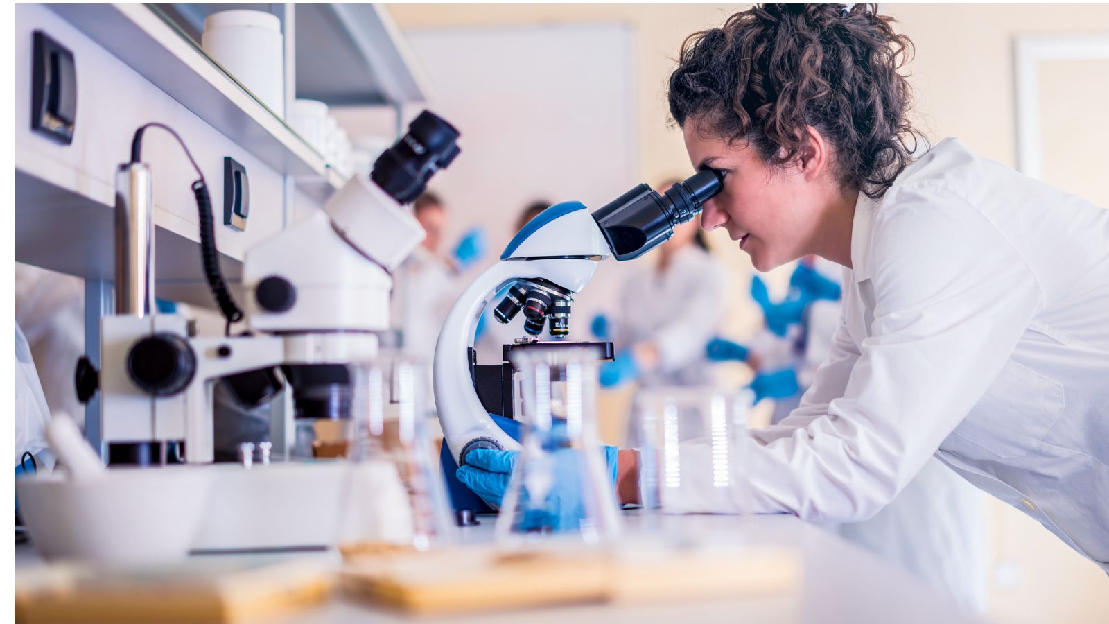 Imagen de una mujer en un laboratorio mirando por el microscopio
