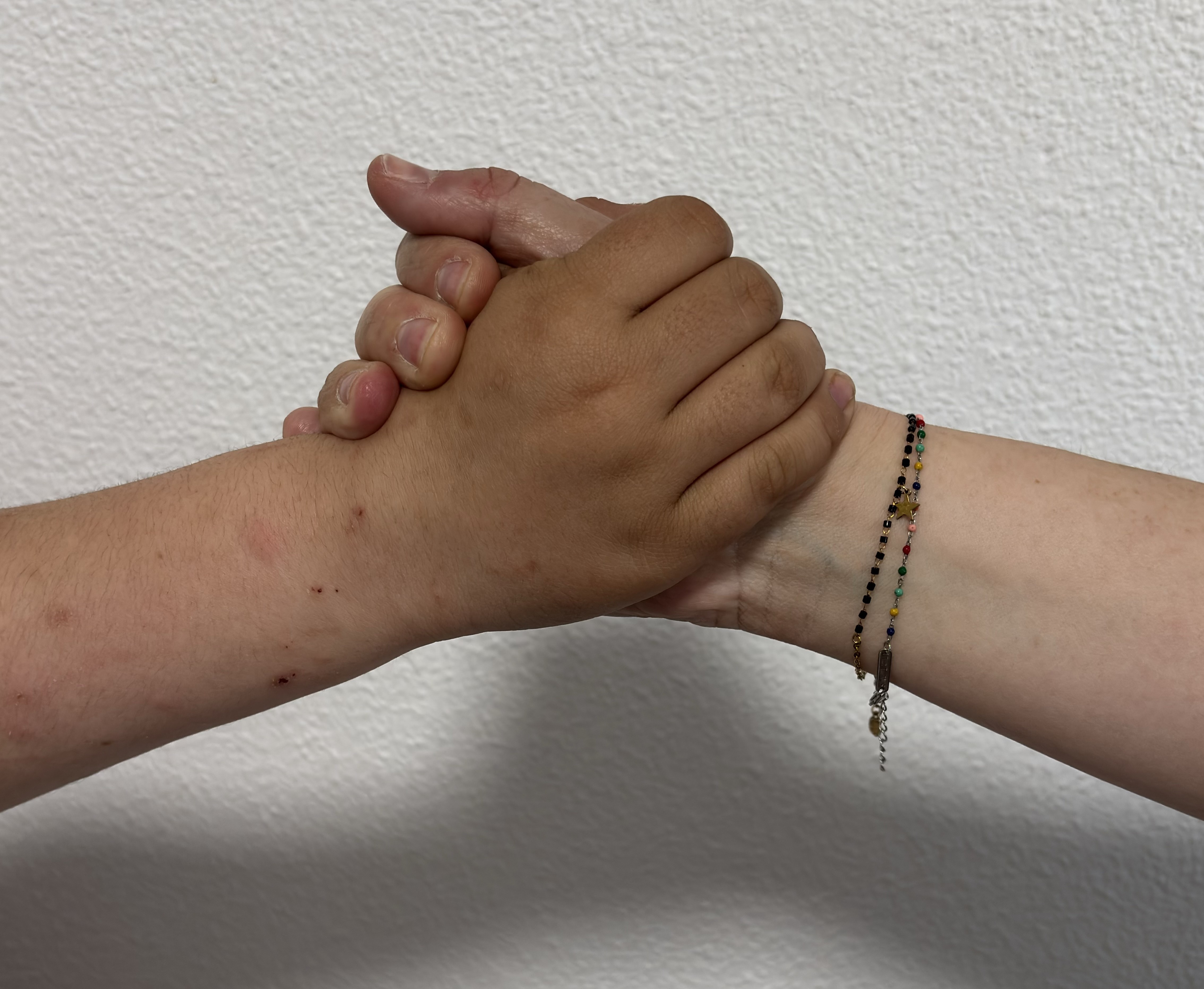 Dos manos de personas distintas, entrelazadas en un gesto de apoyo, sobre un fondo blanco