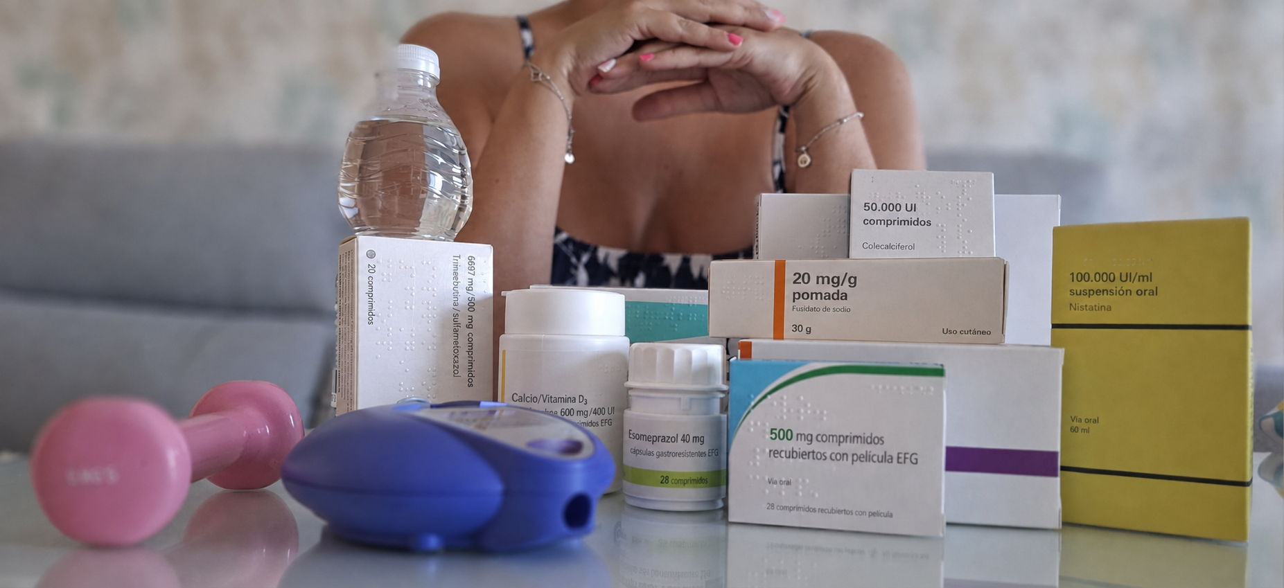 Imagen de una persona a la que no se le ve la cara, rodeada de medicamentos 