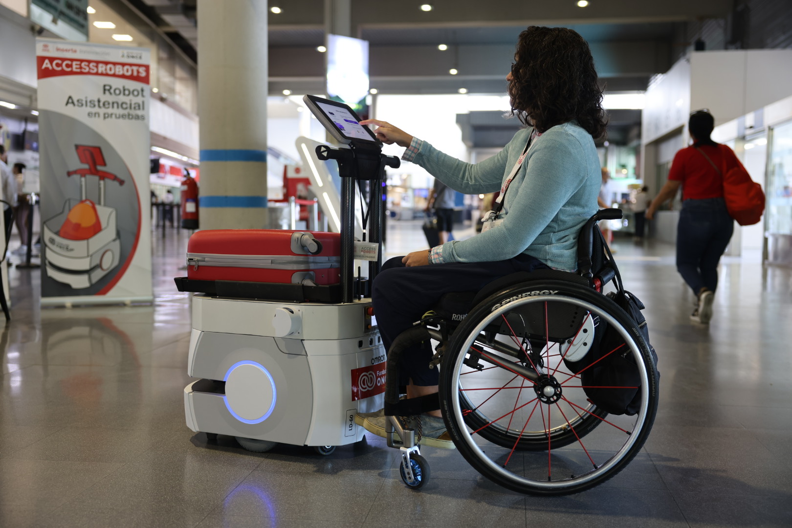 Usuaria en silla de ruedas manejando la pantalla de un robot en un entorno real  