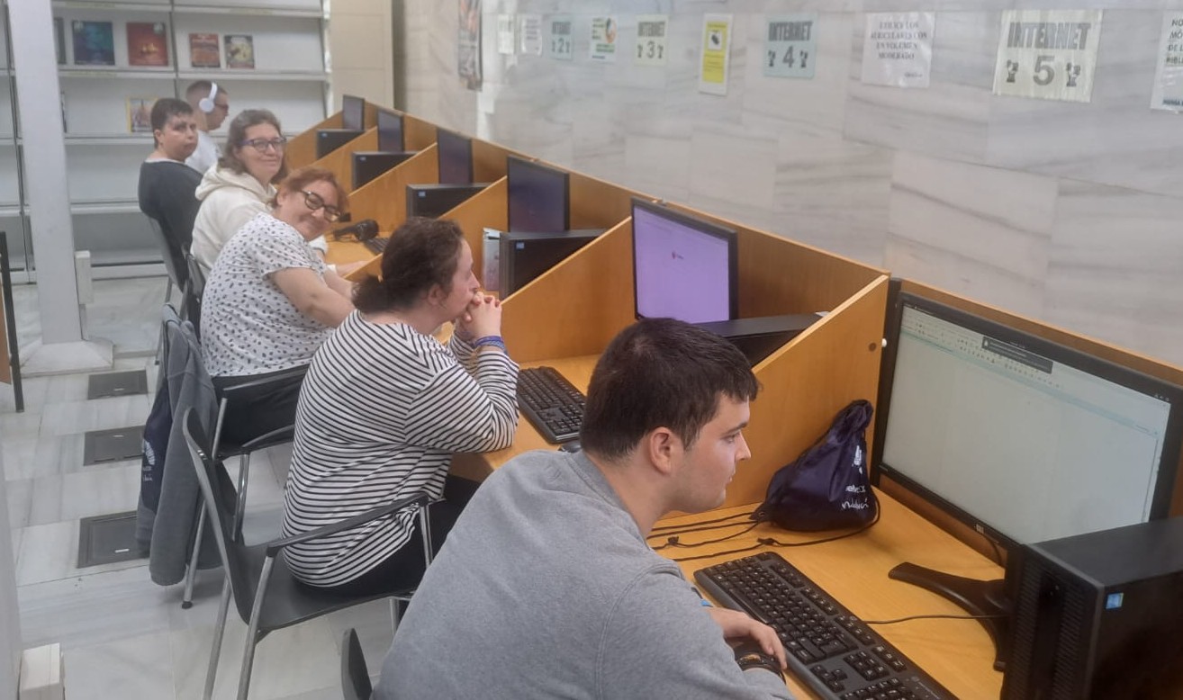 Miembros del Centro Residencial Tartesos en la Biblioteca Pública del Estado en Huelva sentados frente ordenadores