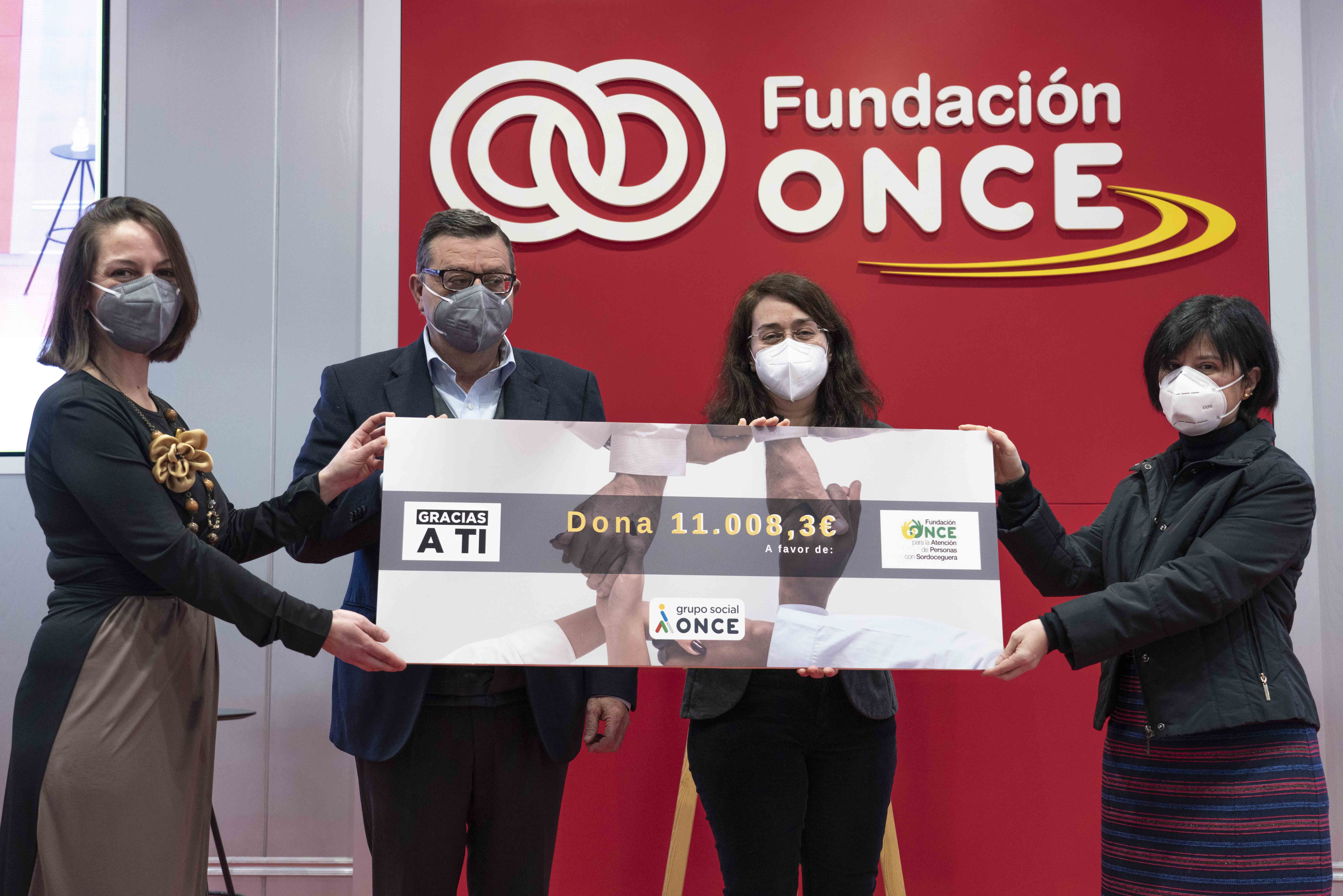 Foto en la que se ve a Paloma y a José Luis Martínez Donoso entregando el cheque solidario a los representantes de FOAPS