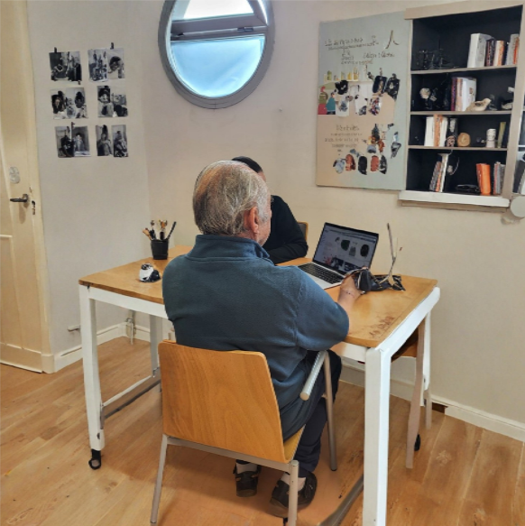 Imagen modificada con IA en la que se ve a una persona atendiendo a otra tras una mesa con un ordenador