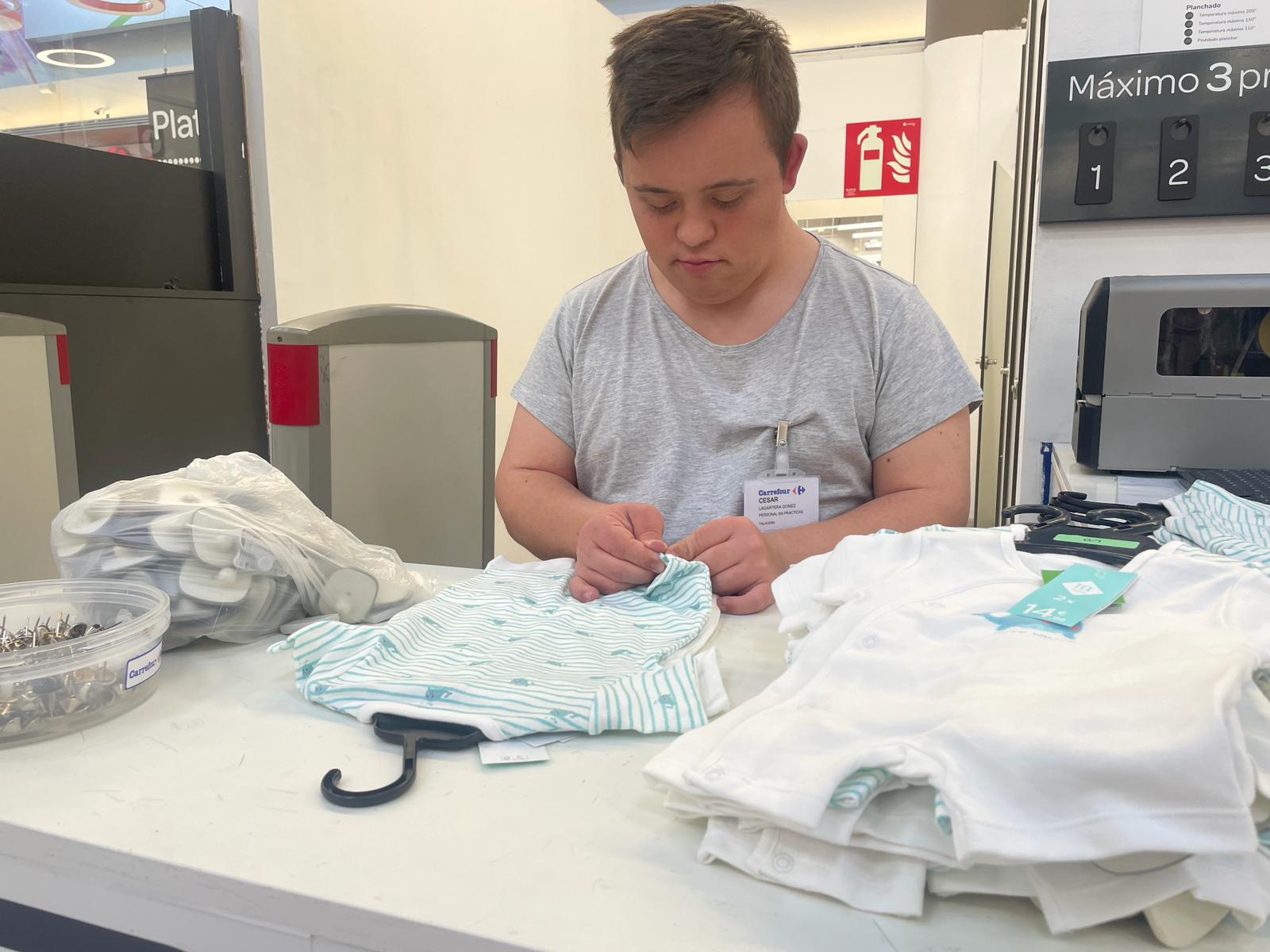 Foto de César poniendo la alarma a una prenda de ropa durante sus prácticas en Carrefour 