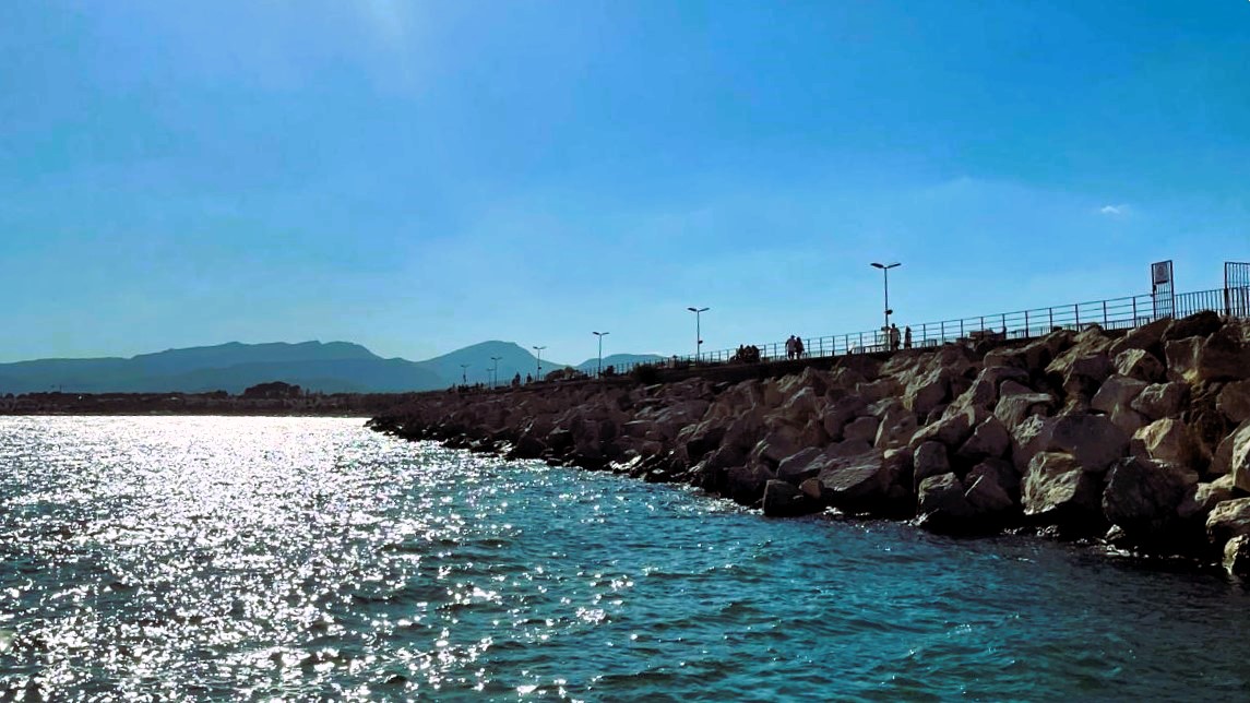 Imagen de un paisaje costero en la que se ve el mar y un rompeolas que se extiende hacia el horizonte