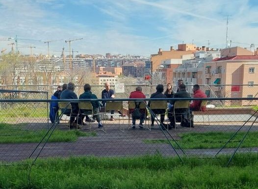 Imagen de un grupo del Club de Lectura de la biblioteca Ana María Matute debatiendo sentados en sillas al aire libre