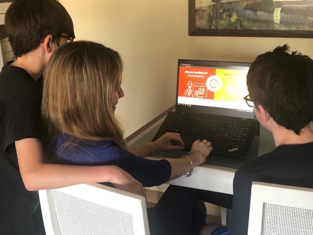 Imagen de María ante el ordenador rodeada de sus hijos 