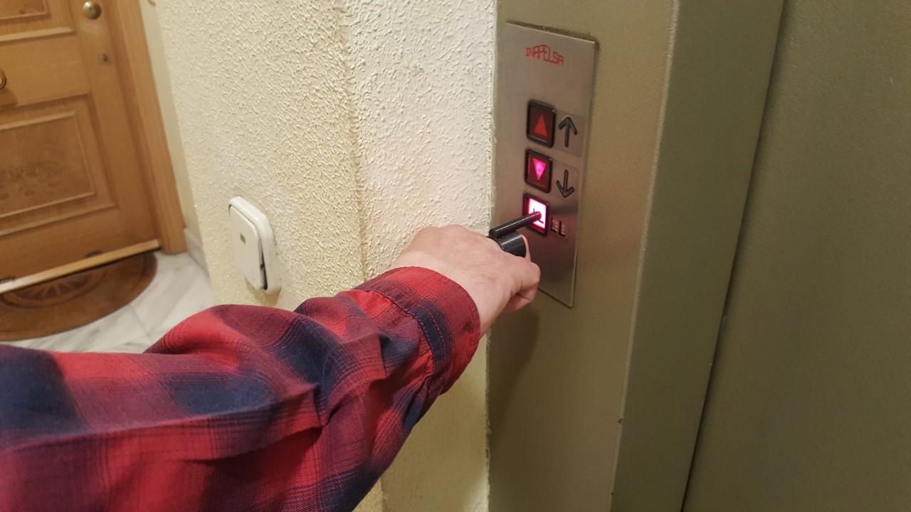 Imagen de un dedo pulsando el botón de un ascensor con una pieza de impresión 3D