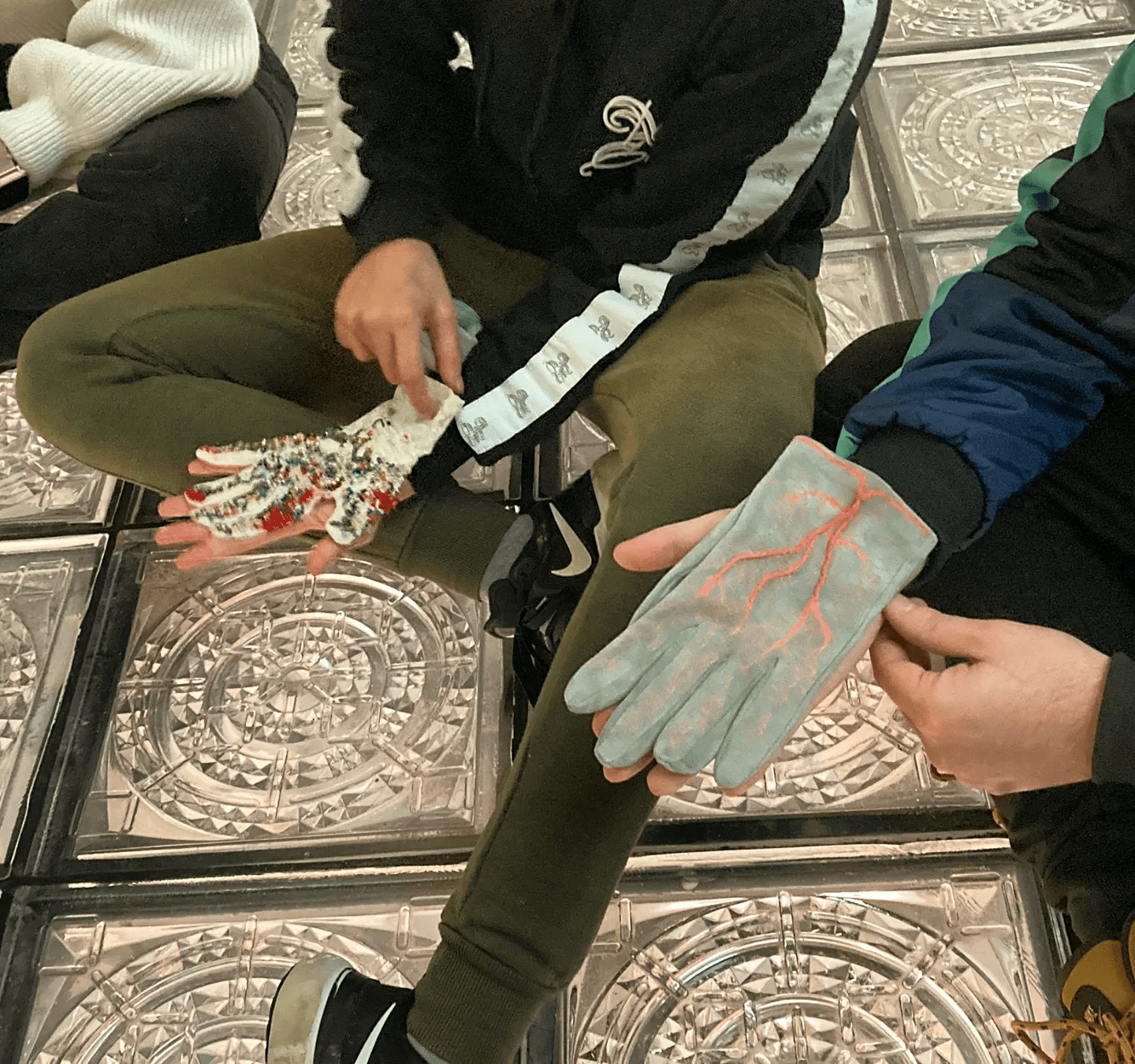 Foto en la que aparecen dos personas con dos guantes diferentes hechos a mano