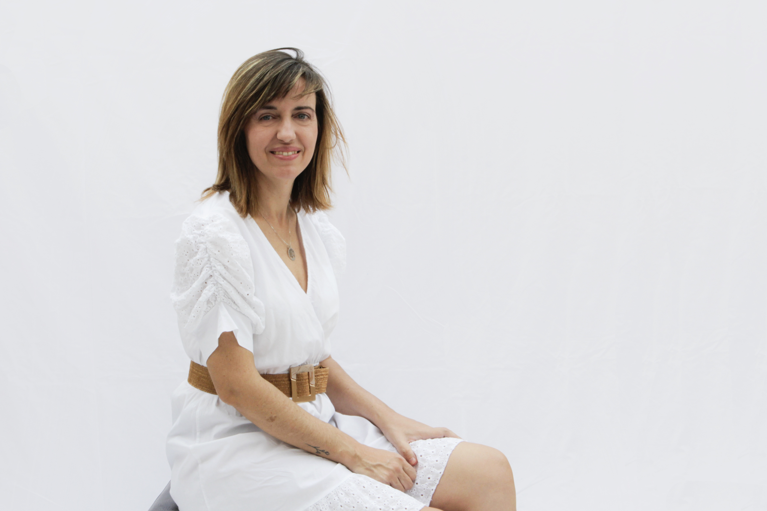 Imagen de María sentada, vestida de blanco y con las manos en las rodillas
