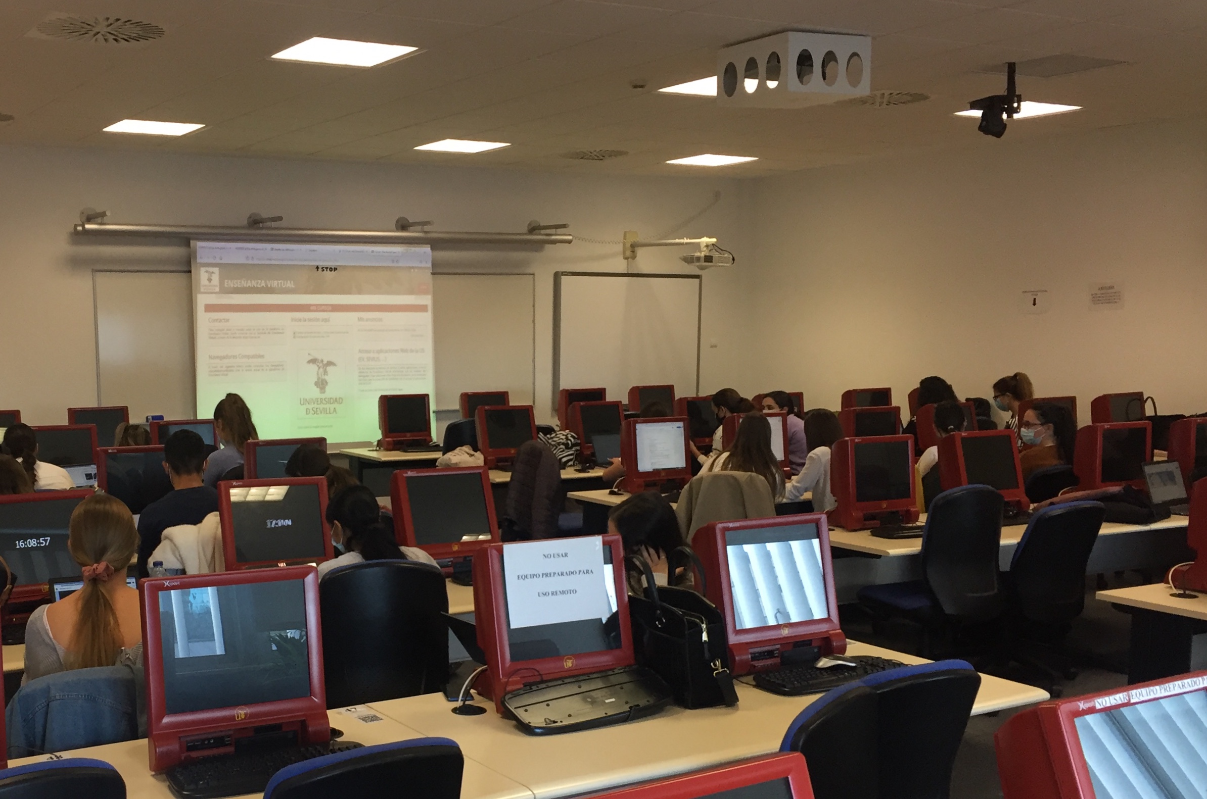 Imagen de un aula en la que se ven pantallas en los pupitres