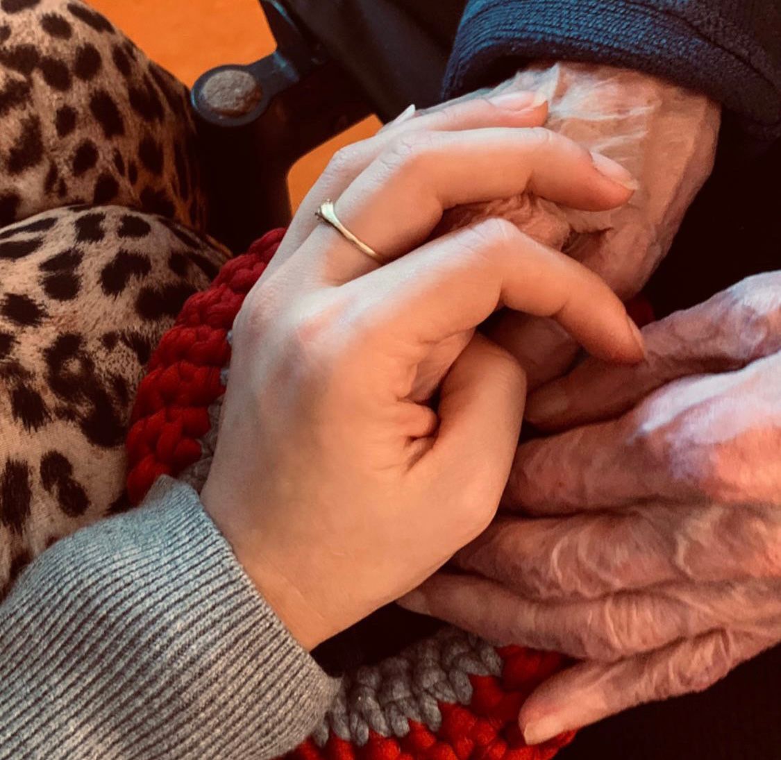 Imagen de una mano sobre las manos de una persona mayor 