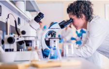 Imagen de una mujer en un laboratorio mirando por el microscopio