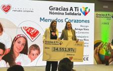 Foto de Andrea entregando un cheque gigante a la representante de Menudos Corazones en el que se le la cifra donada: 34.551,97 