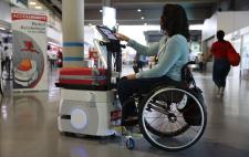 Usuaria en silla de ruedas manejando la pantalla de un robot en un entorno real  