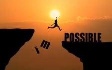 Silueta de una persona saltando entre dos acantilados al atardecer, donde las letras 'i' y 'm' caen del acantilado izquierdo transformando la palabra 'impossible' en 'possible' en el acantilado derecho