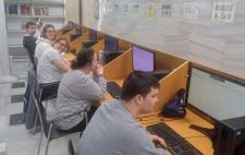 Miembros del Centro Residencial Tartesos en la Biblioteca Pública del Estado en Huelva sentados frente ordenadores