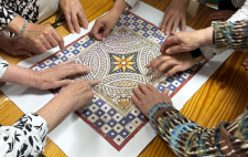 Imagen de varias manos de personas mayores alrededor de un mosaico de papel con un diseño geométrico