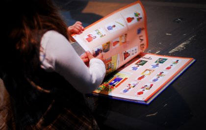 Imagen de una niña manejando un libro con pictogramas 