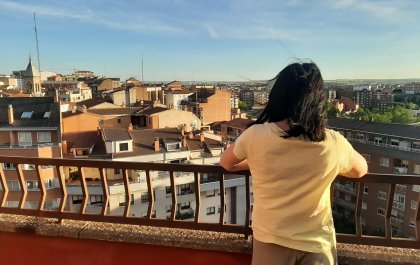 Foto de Sara de espaldas, asomada a un mirador por el que se ven las casas de un pueblo o ciudad