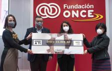 Foto en la que se ve a Paloma y a José Luis Martínez Donoso entregando el cheque solidario a los representantes de FOAPS