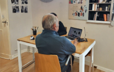 Imagen modificada con IA en la que se ve a una persona atendiendo a otra tras una mesa con un ordenador