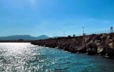 Imagen de un paisaje costero en la que se ve el mar y un rompeolas que se extiende hacia el horizonte