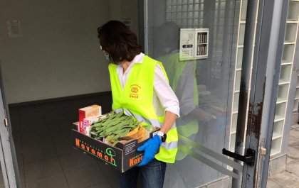 Imagen de una voluntaria de Fundación ONCE llevando una caja de comida a un domicilio 