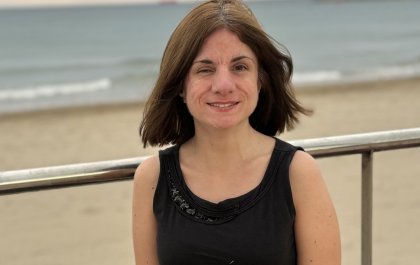 Foto de Elena sentada con el mar al fondo y el cielo nublado 