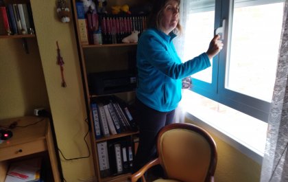 Imagen de Raquel, de pie delante de una estantería con libros y ante una ventana que va a abrir