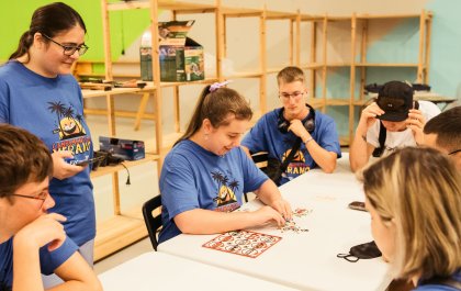 Foto en la que se ve a Xabela junto a un grupo de compañeros alrededor de una mesa en la que hay un juego durante el campamento 