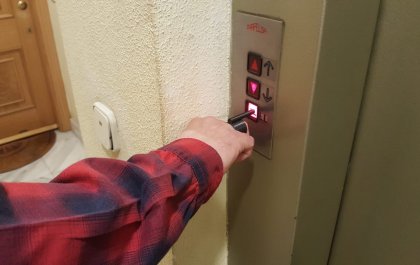 Imagen de un dedo pulsando el botón de un ascensor con una pieza de impresión 3D