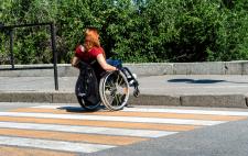 Imagen de Lucía de espaldas en su silla de ruedas curzando un paso de peatones Imagen de Lucía de espaldas en su silla de ruedas curzando un paso de peatones
