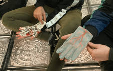 Foto en la que aparecen dos personas con dos guantes diferentes hechos a mano 