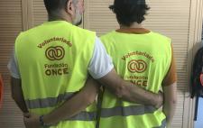 Imagen de dos personas entrelazadas por la espalda con el chaleco del voluntariado de Fundación ONCE