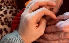 Imagen de una mano sobre las manos de una persona mayor 