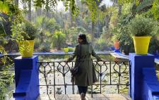 Virginia de espaldas, apoyada en una barandilla que deja ver un paisaje verde