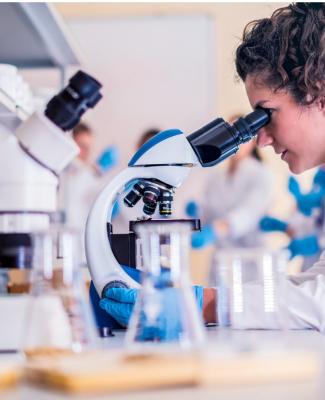 Imagen de una mujer en un laboratorio mirando por el microscopio