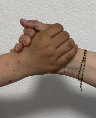 Dos manos de personas distintas, entrelazadas en un gesto de apoyo, sobre un fondo blanco
