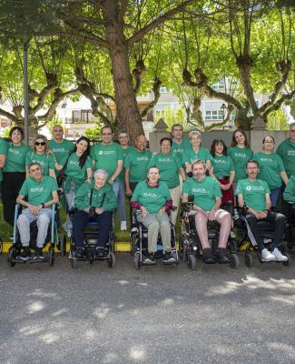 Grupo de personas en silla de ruedas con camisetas o sudaderas verdes que llevan leyendas relacionadas con la ELA 