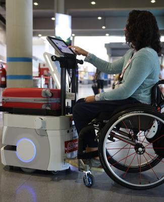 Usuaria en silla de ruedas manejando la pantalla de un robot en un entorno real  
