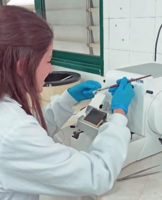 Elena con bata blanca y guantes azules manipulando material en el laboratorio   