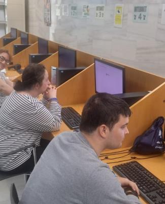 Miembros del Centro Residencial Tartesos en la Biblioteca Pública del Estado en Huelva sentados frente ordenadores