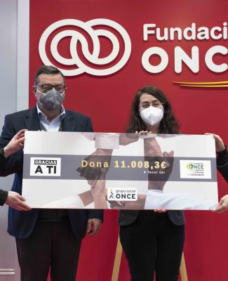 Foto en la que se ve a Paloma y a José Luis Martínez Donoso entregando el cheque solidario a los representantes de FOAPS