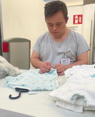 Foto de César poniendo la alarma a una prenda de ropa durante sus prácticas en Carrefour 