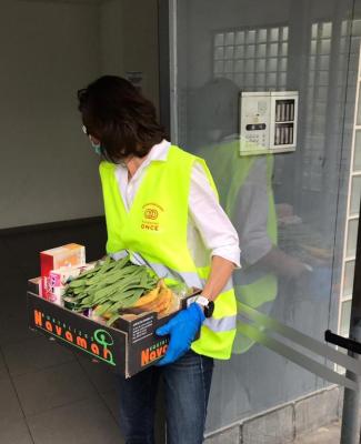 Imagen de una voluntaria de Fundación ONCE llevando una caja de comida a un domicilio 