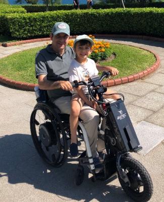 Enrique en silla de ruedas con su hijo sentado encima