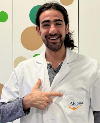Foto de Juandi señalando el bolsillo de su bata blanca, en el que se lee "Aladina Fundación"