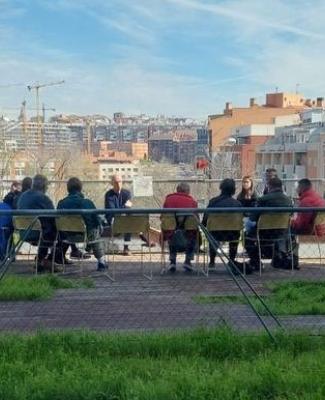 Imagen de un grupo del Club de Lectura de la biblioteca Ana María Matute debatiendo sentados en sillas al aire libre